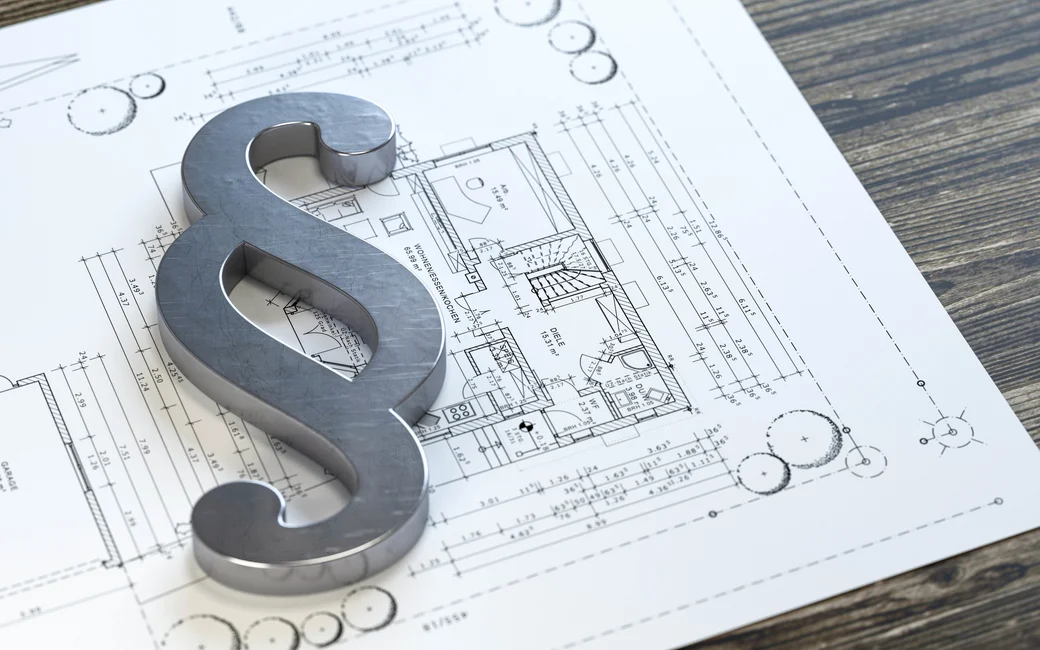 Ein Paragraphen-Zeichen liegt auf einem Grundriss