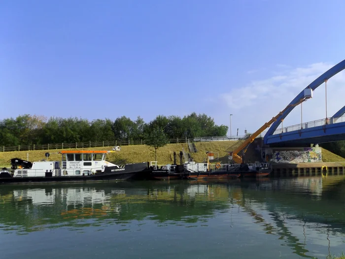 Von einem Schiffsrumpf wird eine Hebebühne an eine Brücke ausgefahren